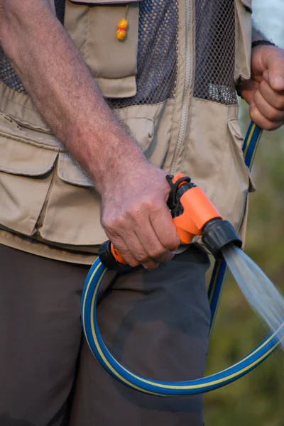  Emekli bahçıvan bahçe hortumu ile sulama. 