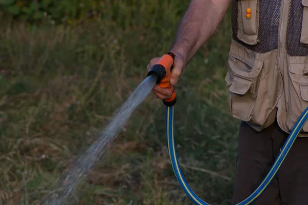  Emekli bahçıvan bahçe hortumu ile sulama. 