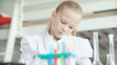 Kimya deneyi yapan kız. Test tüpü ile masanın üzerinde durun