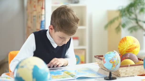 De jongen ziet Atlas met kaarten. School jongen leert Geografie. — Stockvideo