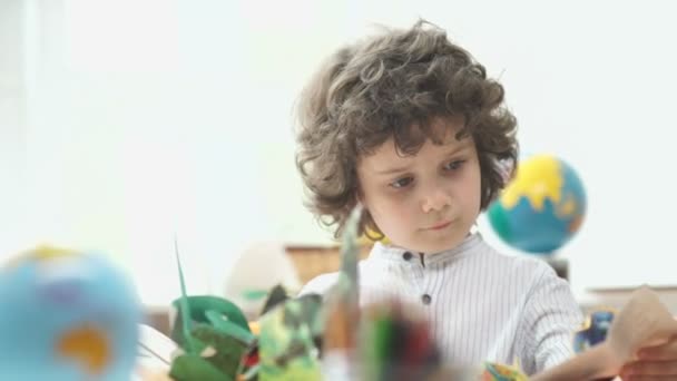 Jongen met zwarte krullend haar blik boek met Foto's. — Stockvideo