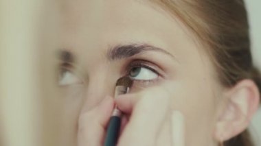 Makyaj sanatçısı makyaj için bir fırça kullanarak alt göz kapağı üzerinde incili gölge yok.