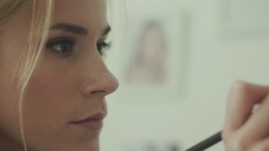 Odaklanmış görünüm. Gözler ok. Fırça kullanan makyaj sanatçısı