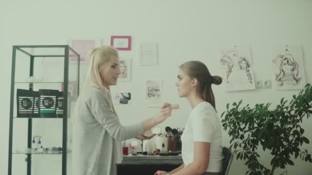 La modelo sentada en una silla frente a un maquillador. Trabajos de maquillaje — Vídeos de Stock