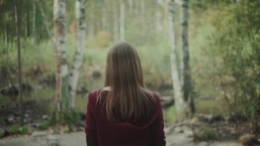 Kız gölete bakıyor. Yalnız yürüyor..