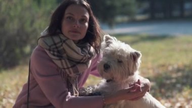 Young woman with a beautiful smile, walking with a dog in the sunny day