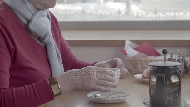 Pensionären ger muggen te till hennes läppar, tar en klunk — Stockvideo