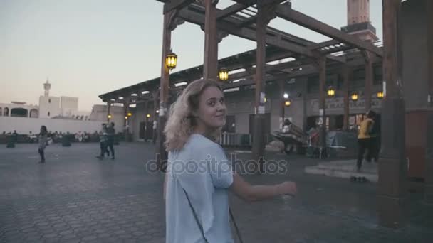 Blonde met krullend haar gaat langs de smalle Oost-markt — Stockvideo