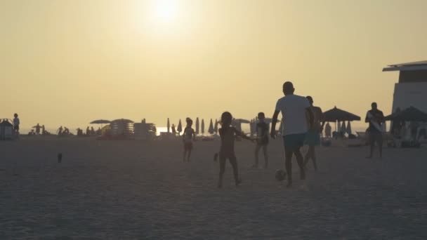 Silhuetas de adolescentes e crianças brincando no mar com a bola — Vídeo de Stock