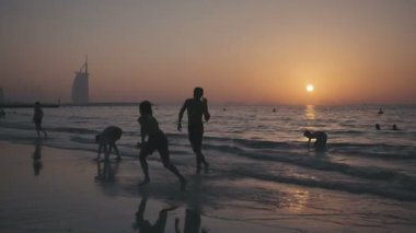 İnsanlar ve turistler Basra Körfezi'nin kıyısında siluetleri.