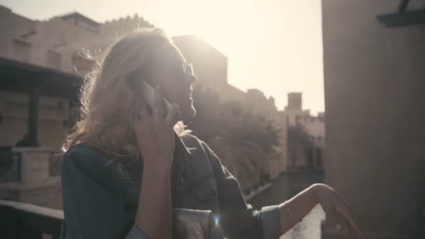 UAE, 2017: Madinat jumeirah. Vrouw in zonnebril praten aan de telefoon. — Stockvideo