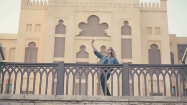 Girl doing selfie in front of famous buildings in Emirates. — Stock Video