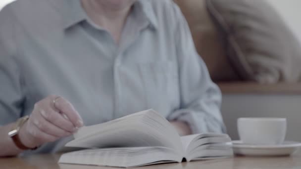Frau mittleren Alters hält ein Buch in der Hand und blättert. — Stockvideo