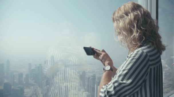 Girl tourist in striped shirt standing at the window and photographed — Stock Video