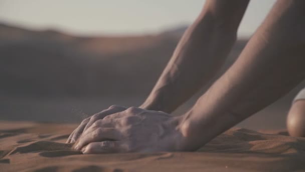 Крупним планом чоловіча рука бере кілька піску в пустелі — стокове відео