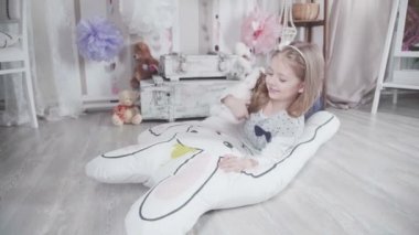 Peluş oyuncaklar ve büyük yumuşak oyuncak tavşan oynarken küçük şirin kız