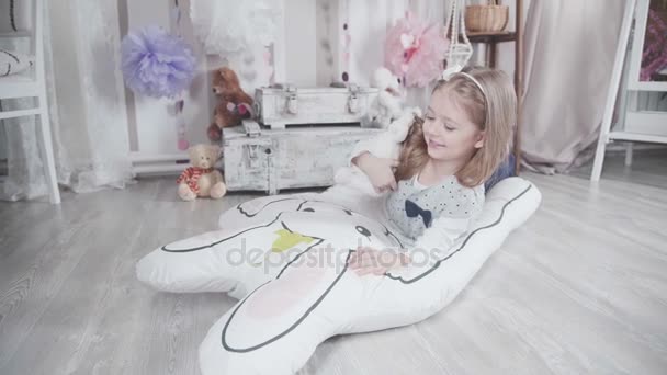 Маленькая милая девочка играет с плюшевыми игрушками и большим мягким зайцем — стоковое видео