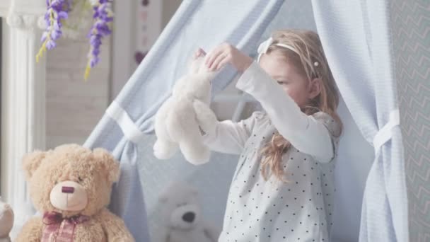 Uma criança brinca com brinquedos, conversa com eles e abraça um brinquedo macio . — Vídeo de Stock