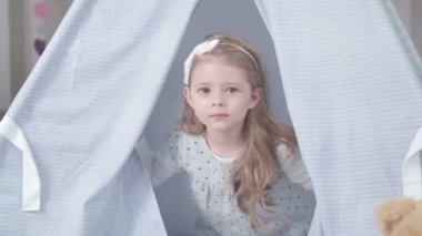 Mutlu çocukluk ve çocuk oyunları. Teepee çadırda küçük kız.