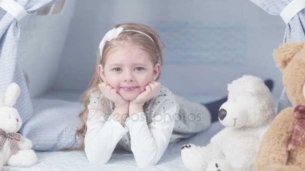 Mädchen liegt im Kinderzimmer auf dem Boden und legt die Hände auf die Wangen — Stockvideo