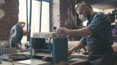 Woodworker veya marangoz ahşap atölyesinde bir tahta üzerinde çalışıyor