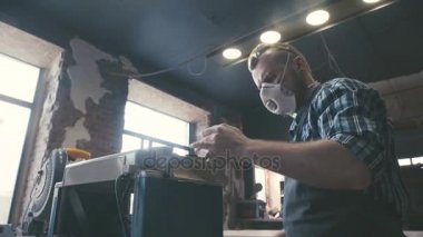 Marangoz ahşap bir parça alır ve testere ile geçer