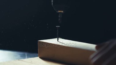 Ahşap plaka üzerinde bir çelik matkap ve her zamanki tornavida kullanarak adam