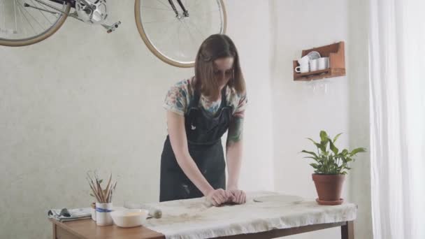 Młoda kobieta w stylowe fartuch jest zaangażowany w stylowe studio ceramiczne. — Wideo stockowe