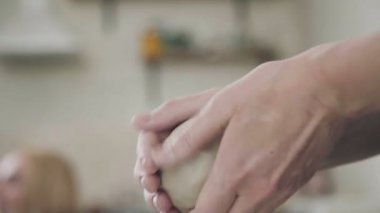 Yakın çekim: bir kadın ustası elinde beyaz kil bir yumru.