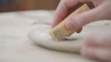 Potter Beyaz kil - yuvarlak tabak ve sünger kullanarak bir ürün yapar