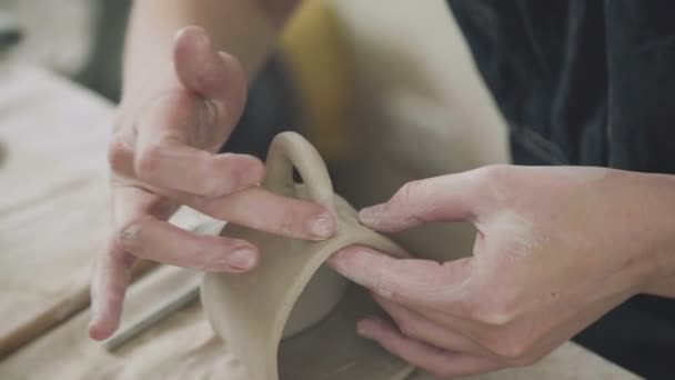 Жінка-гончар робить глиняний кухоль і палички ручки. Керамічний посуд ручної роботи — стокове відео