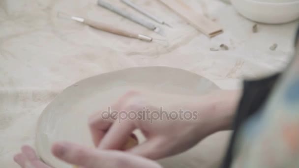 Potter hace un producto hecho con arcilla blanca - una placa redonda. Trabajos de cerámica . — Vídeo de stock
