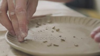 Potter kil desen plaka üzerinde yığın kullanarak yapar.