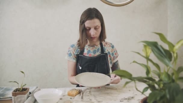 Женщина гончар показывает готовый продукт - керамическая плита — стоковое видео