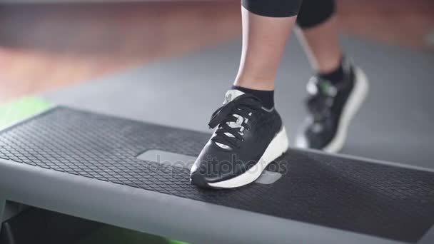 Крупный план женской черной спортивной обуви, наступающей на ступенчатую платформу — стоковое видео