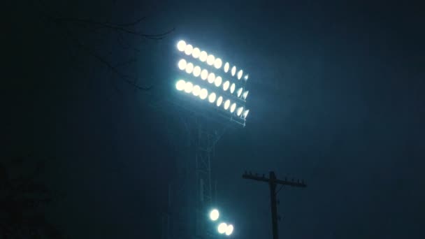 Een felle schijnwerper op een sport stadion schittert in de donkere hemel. — Stockvideo