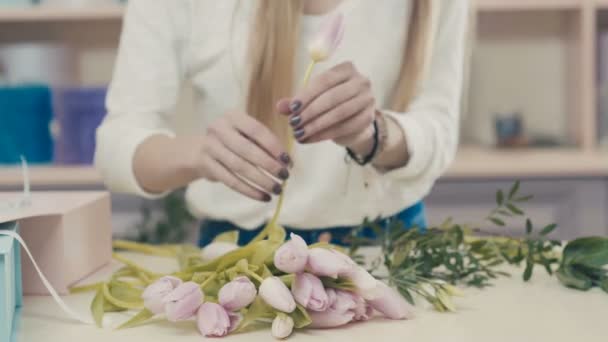 Florist at work at the ounter makes a bouquet of pink tulips. — Stock Video