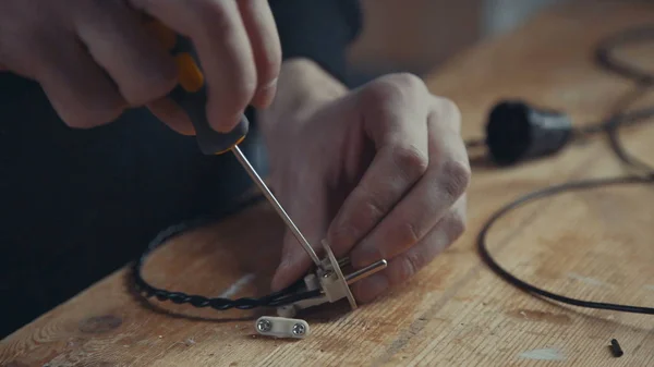 Yakın çekim bir el elektrikçi kablo üzerinde bir tornavida ile çalışma