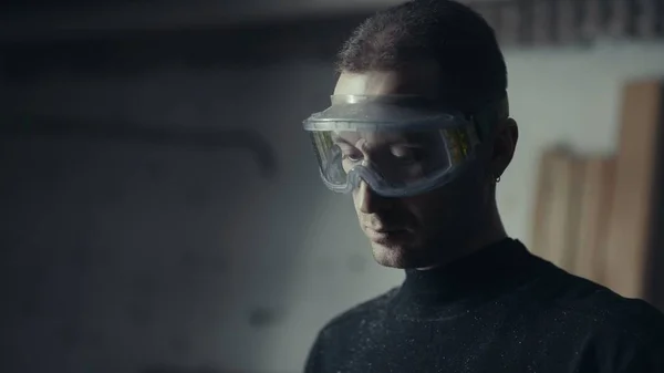 Usta iş istasyonunda kaydedilmiş gözlüklü. Koruyucu maskeli adam