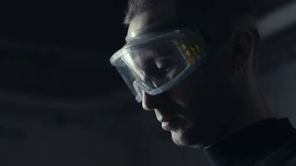 Omul într-o mască de protecție pe un fundal întunecat care lucrează la un instrument electric fotografii de stoc fără drepturi de autor