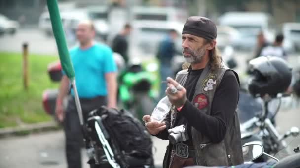 Novosibirsk 2016: Man biker in a leather bandanna and a waistcoat smoking — Stock Video