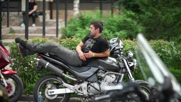Novosibirsk 2016: El hombre con una camiseta negra está acostado a lo largo de una motocicleta — Vídeos de Stock