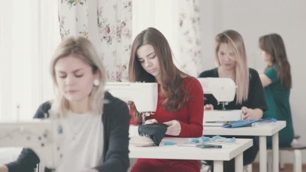Meisjes naaisters zitten achter elkaar en naai de naaimachines. — Stockvideo