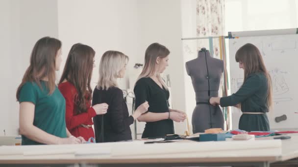 Seamstress Shows A Group Of Girls How To Take Measurements On A Dummy
