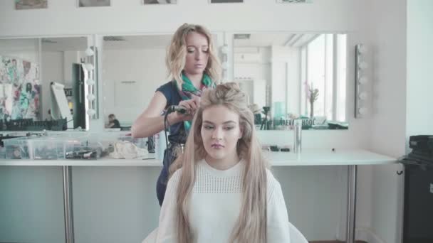 Friseur-Stylistin stylt das Mädchen mit Haarstyling. — Stockvideo