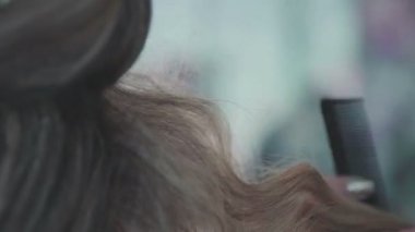 Elektrik kıvırıcı kullanarak yapma saç stilisti bukleler.