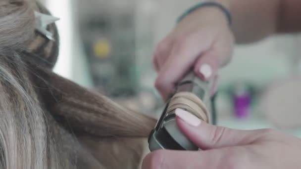 Kapper doet een kapsel - krullen, met behulp van een krultang — Stockvideo