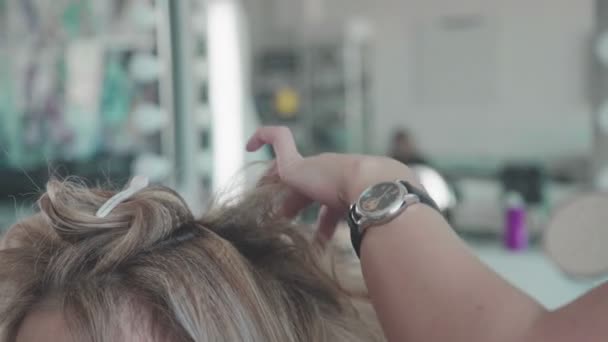 Primer plano de una mujer peluquera haciendo rizos en el pelo rubio — Vídeos de Stock