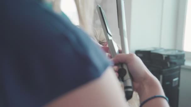 Haarstylist ringetjes aanbrengen blondy vrouw. Tot vaststelling van de haren. — Stockvideo