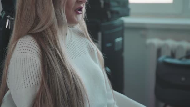 Jovem mulher de cabelos justos em uma camisola branca veio ao salão de beleza — Vídeo de Stock